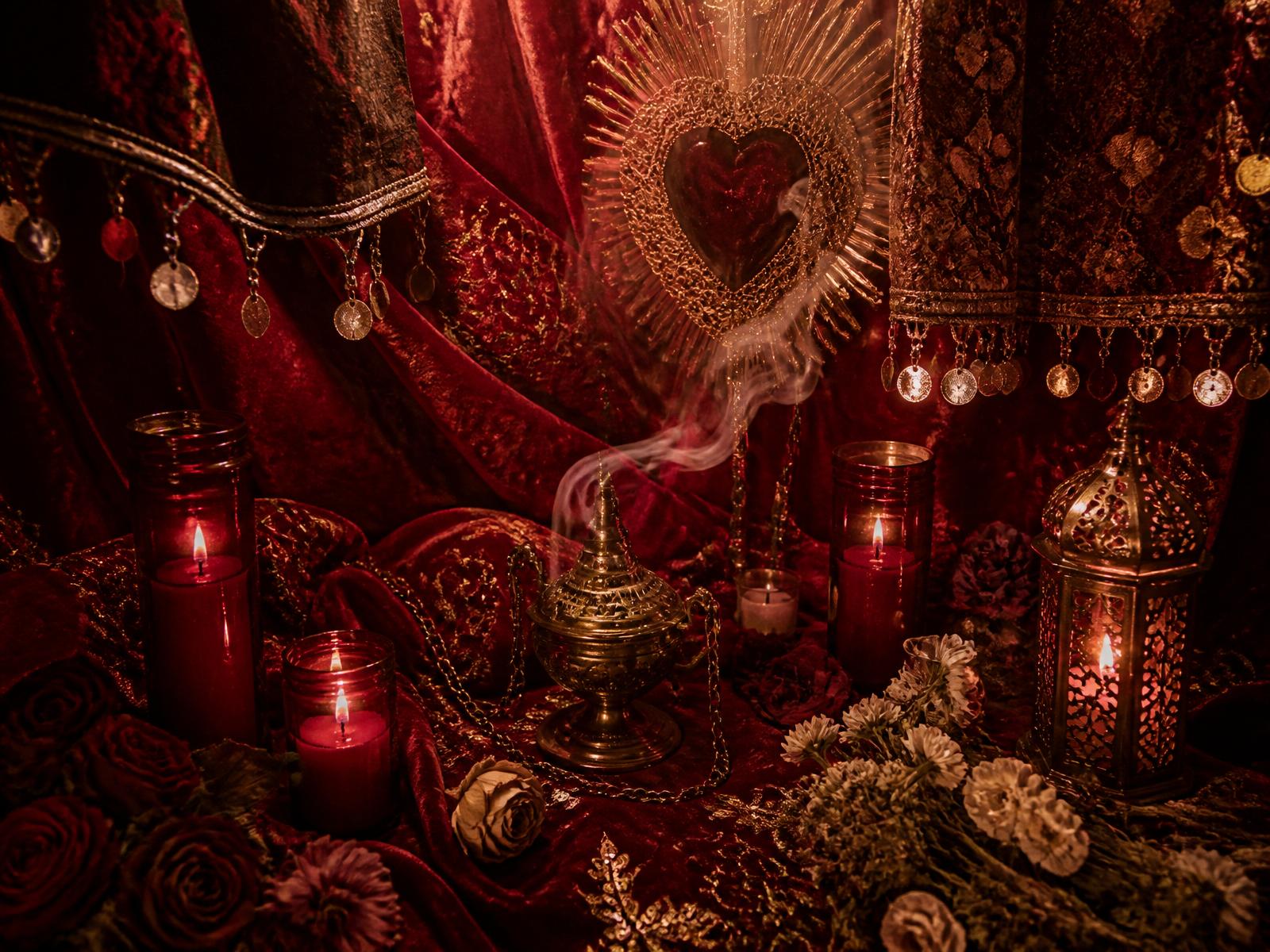 Altar com velas vermelhas, lenços ciganos bordados e incenso